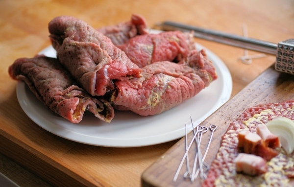 Рулетики из свинины на большой белой тарелке