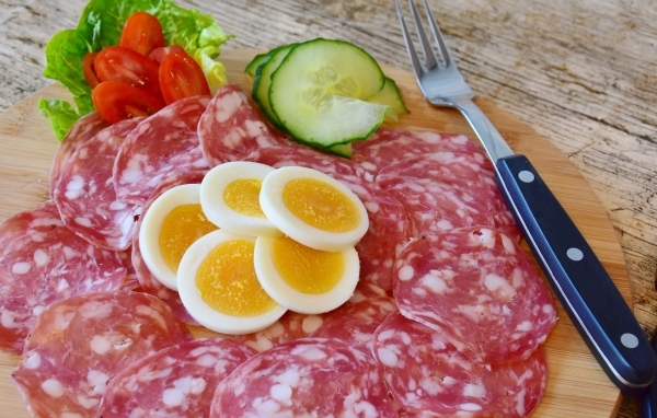 Колбаса салями на доске с вареными яйцами и овощами