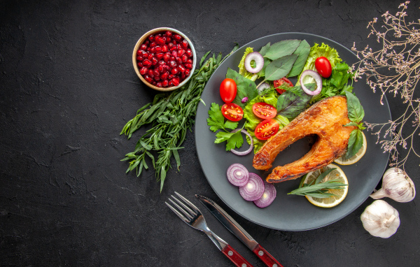 Жареная рыба на тарелке с овощами и зеленью