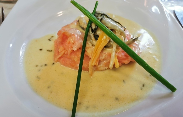 Красная рыба с соусом на тарелке с зеленым луком