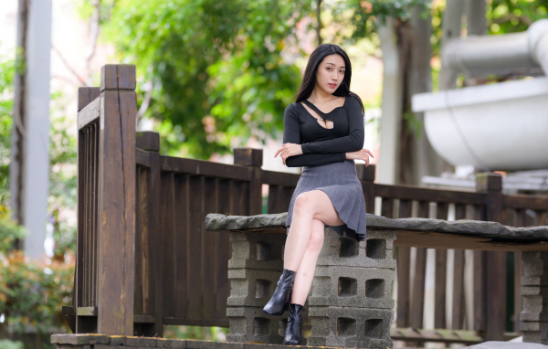 Девушка в короткой юбке сидит на лавке