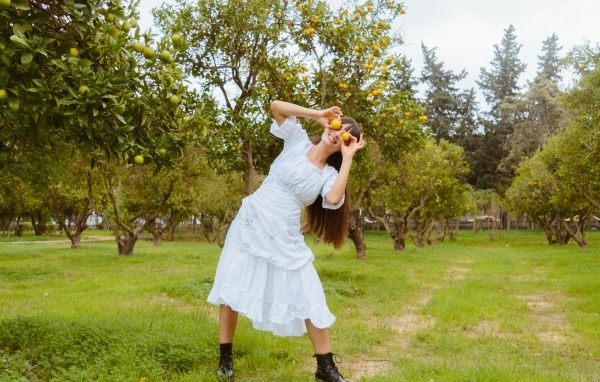 Девушка в белом платье закрыла глаза лимонами
