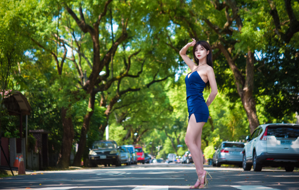 Стройная азиатка в коротком платье стоит на дороге
