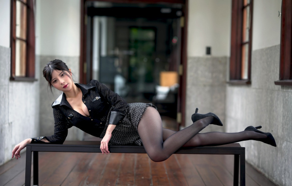 Стройная азиатка лежит на лавке в чулках