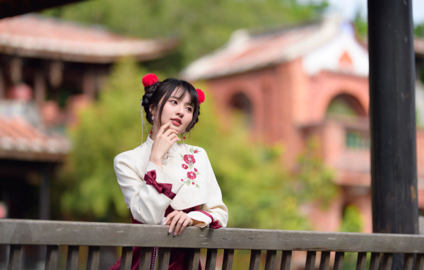 Девушка азиатка в народном костюме стоит у перил