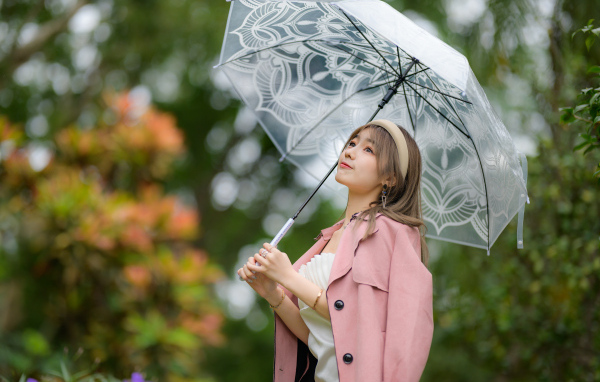 Девушка азиатка в пальто под прозрачным зонтом