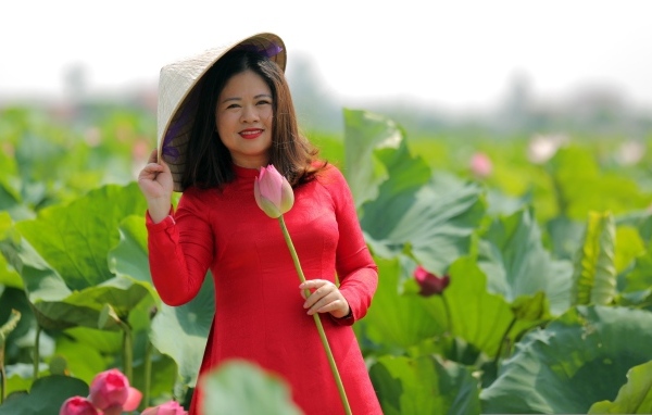 Девушка азиатка в красном платье у цветов лотоса