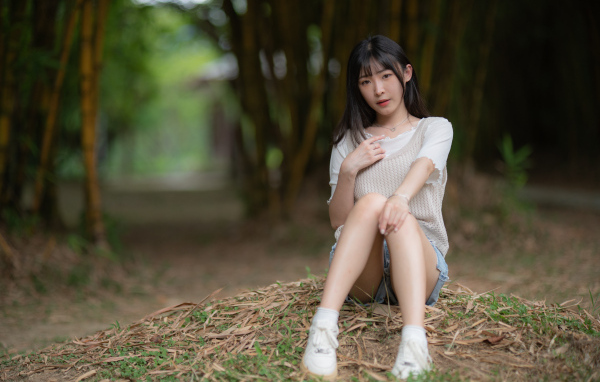 Азиатка сидит на земле в парке