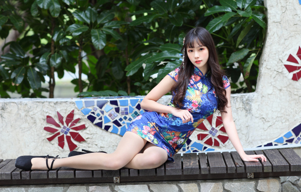 Красивая девушка азиатка в платье лежит на лавке