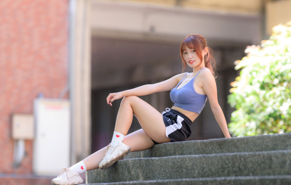Красивая спортивная девушка азиатка сидит на ступеньках