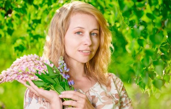 Красивая девушка с цветами люпина в руке