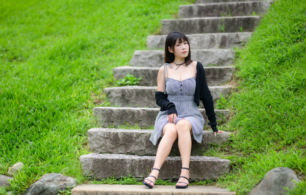 Красивая молодая девушка азиатка сидит на ступеньках
