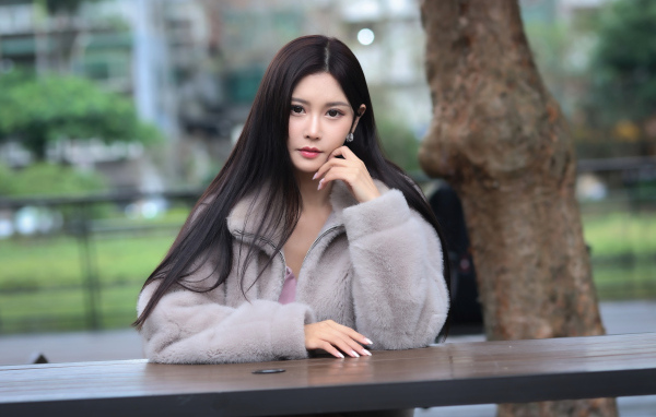 Кареглазая азиатка сидит в парке за столом