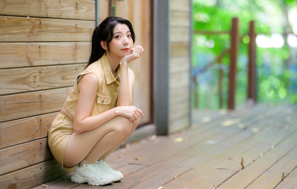 Милая азиатка сидит на корточках у стены