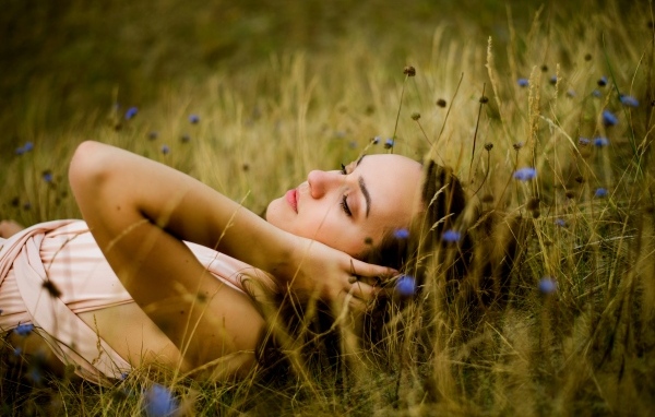 Милая девушка лежит на траве на поле