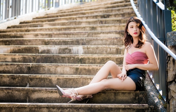 Милая стройная девушка азиатка сидит на ступеньках