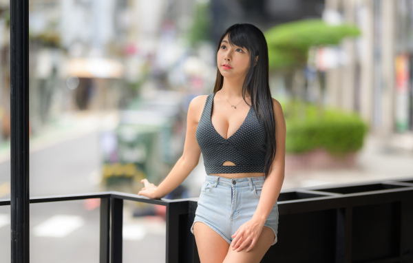Мечтательная девушка азиатка в коротких шортах