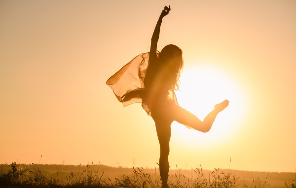 Девушка танцует в лучах солнца на закате