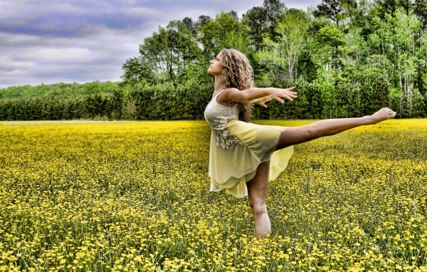 Девушка танцует на поле с желтыми цветами