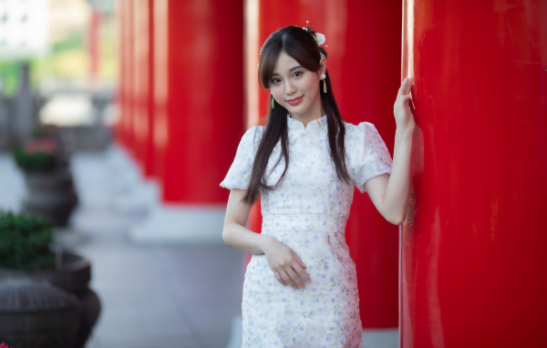 Длинноволосая азиатка позирует у красной колонны