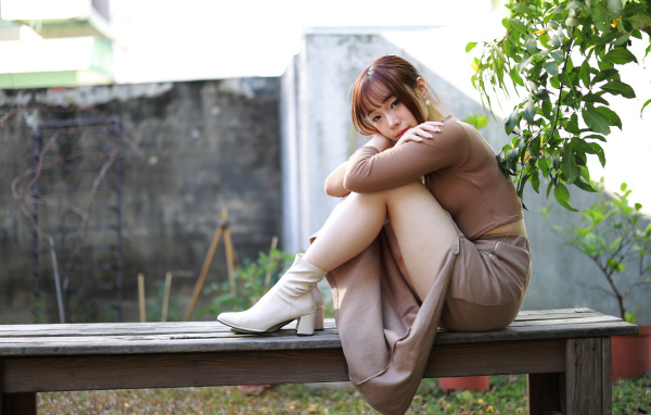 Скромная молодая азиатка сидит на лавке