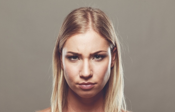 Серьезная девушка с короткой стрижкой на сером фоне