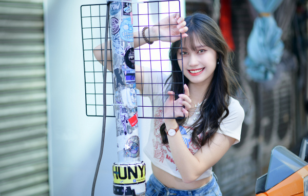 Улыбающаяся азиатка держится за сетку