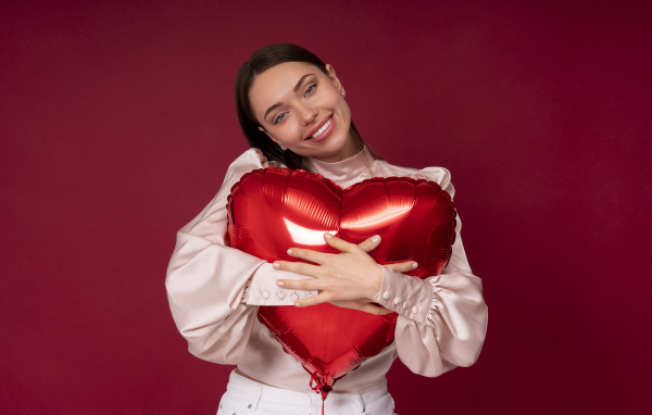 Улыбающаяся девушка обнимает шар в форме сердца