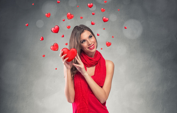 Улыбающаяся девушка в красном платье с сердечками на сером фоне