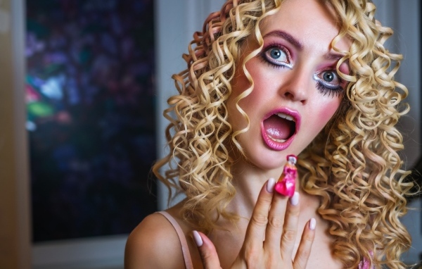 Удивленная девушка блондинка с макияжем куклы