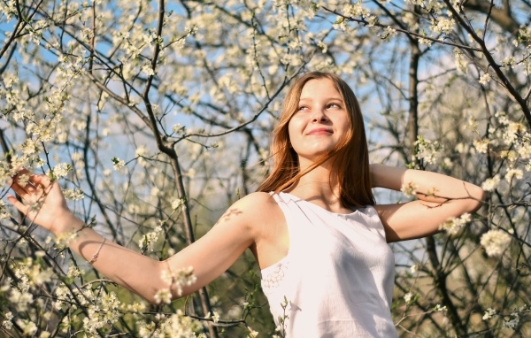 Молодая девушка у цветущего дерева весной