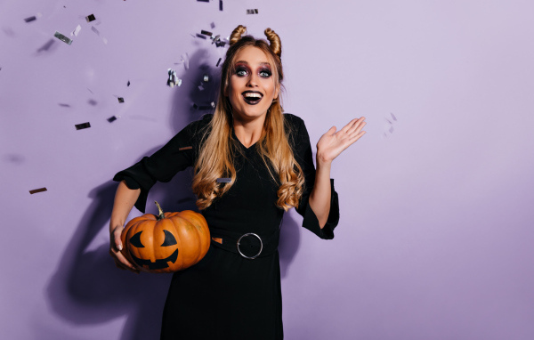 Девушка в черном костюме с тыквой на праздник Хэллоуин