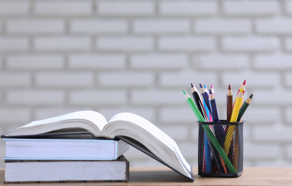 Разноцветные карандаши на столе с книгами 