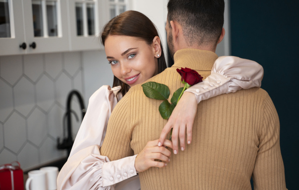 Влюбленная девушка с розой обнимает парня