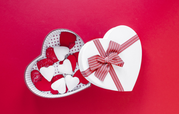 Красивая коробка наполнена сердечками на красном фоне