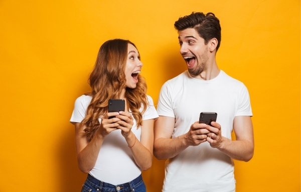 Счастливые парень и девушка с мобильными телефонами