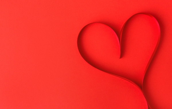 Сердце из атласной ленты на красном фоне