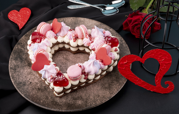 Десерт в форме сердца на столе с красной розой