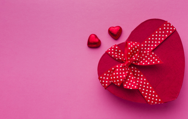 Большая красная коробка в форме сердца на розовом фоне