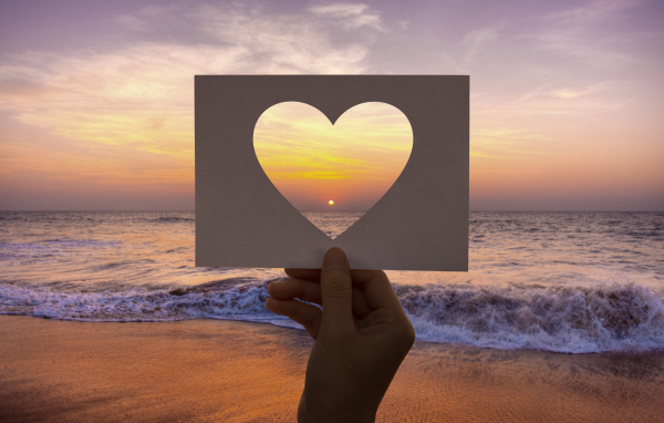 Бумажное сердце на фоне моря на закате солнца