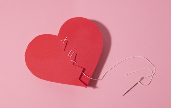 Бумажное сердце сшили нитками на розовом фоне