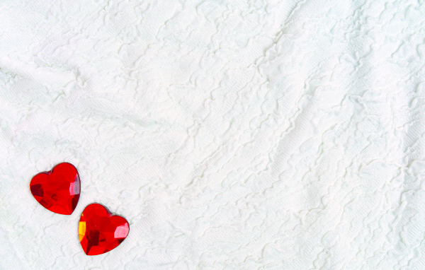 Два красных сердца из пластика на белой ткани
