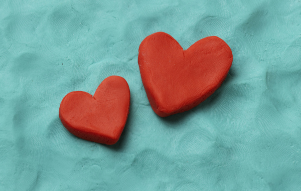 Два красных сердца из пластилина на голубом фоне