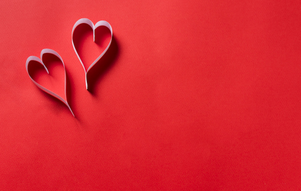 Два белых бумажных сердца на красном фоне