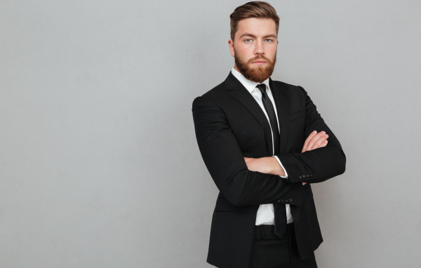 Деловой стильный мужчина в черном костюме на сером фоне