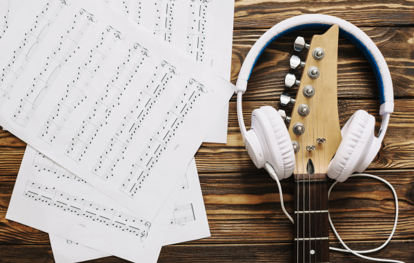 Ноты, наушники и гитара на столе
