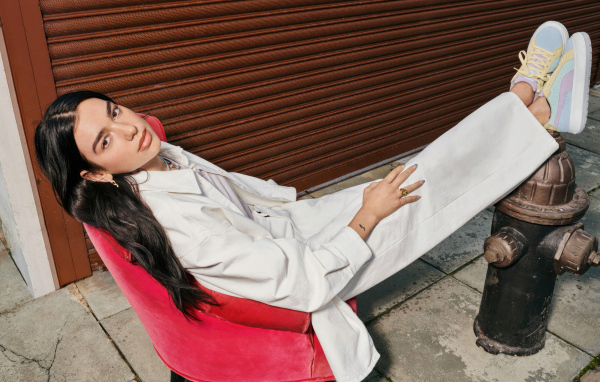 Певица Дуа Липа в белом костюме сидит в кресле