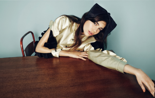 Певица Дуа Липа сидит за деревянным столом