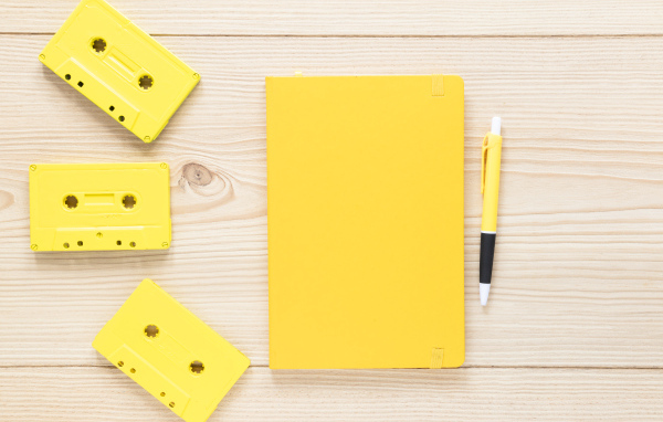 Желтый блокнот с ручкой и кассетами на столе