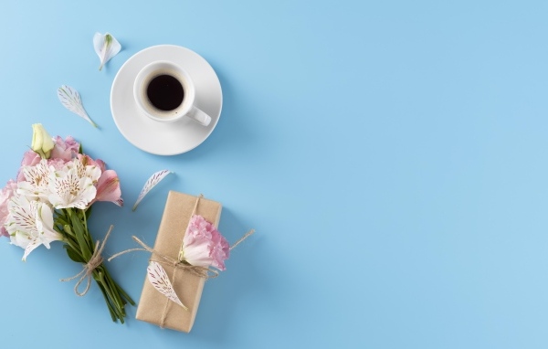 Букет цветов альстромерии с  подарком и чашкой кофе на голубом фоне